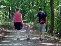 Junge Eltern mit Kind beim Spaziergang im Wald